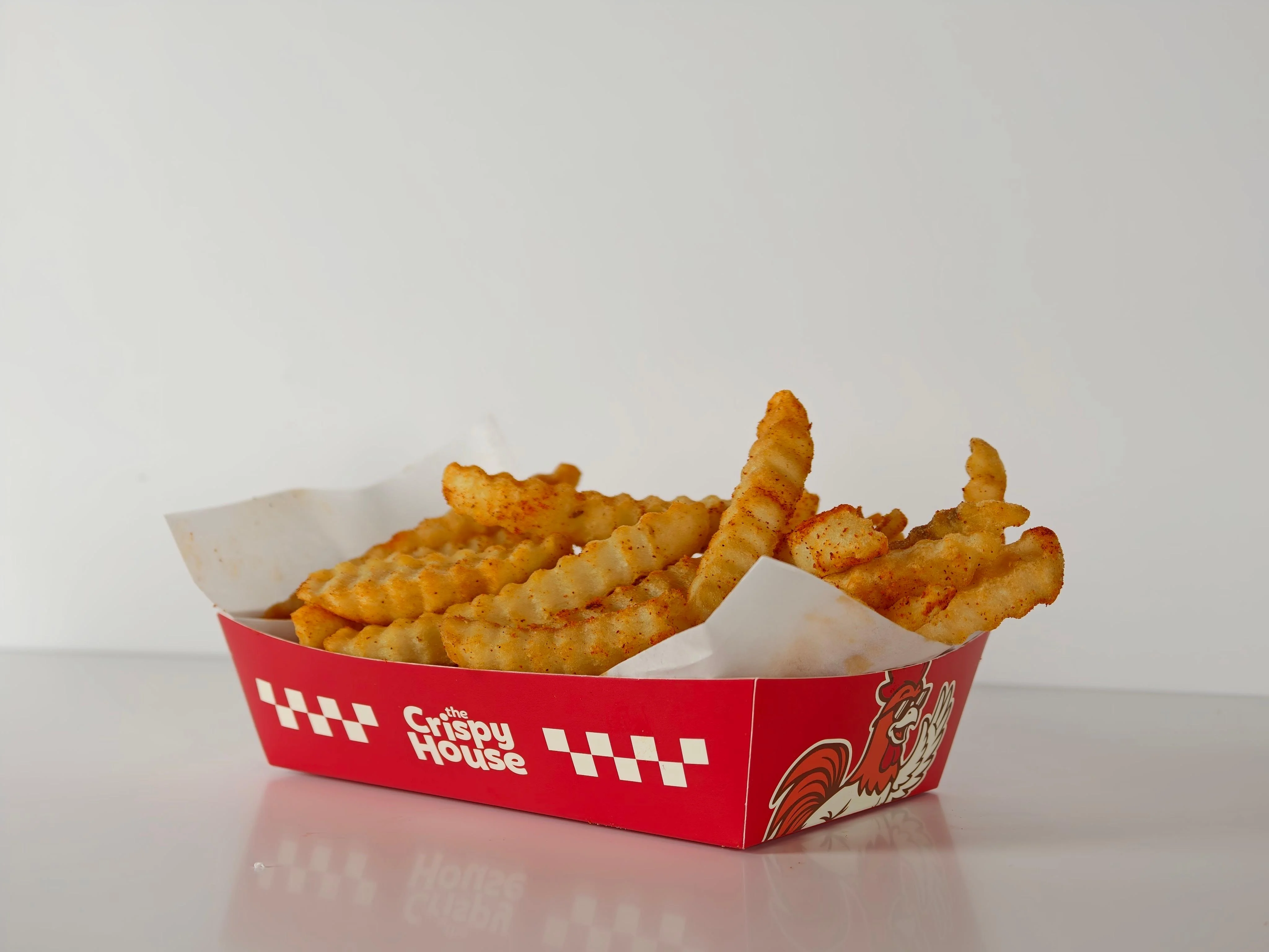 A serving of crinkle-cut fries arranged in a red container, with a crispy texture and golden color.