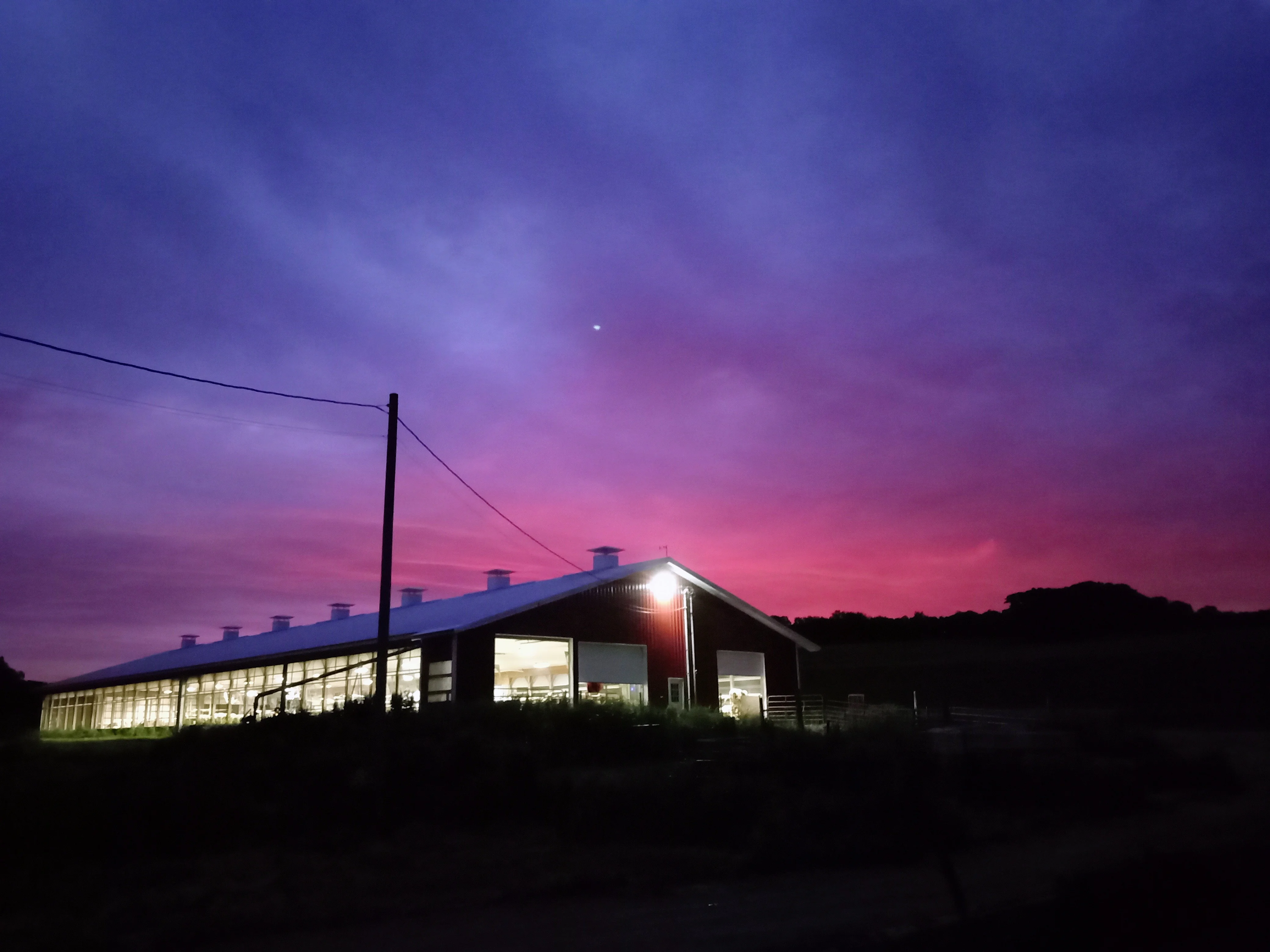 Farm building illuminated at sunset with vibrant purple sky