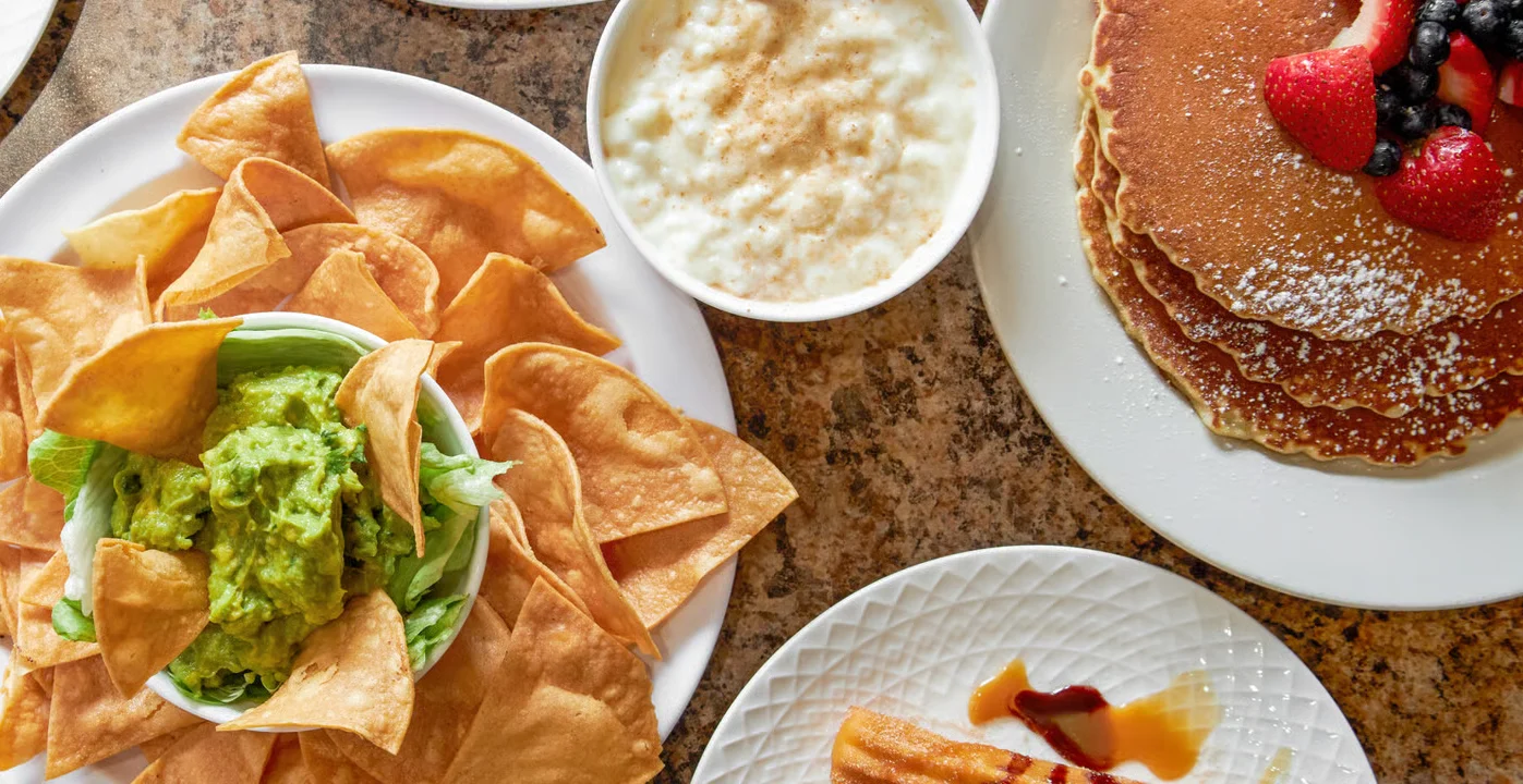 A vibrant spread of popular dishes from El Ranchito Poblano in Brooklyn, highlighting their diverse menu from fresh guacamole to tacos and breakfast pancakes.