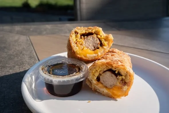 Freshly baked sausage rolls with dipping sauce on a white plate