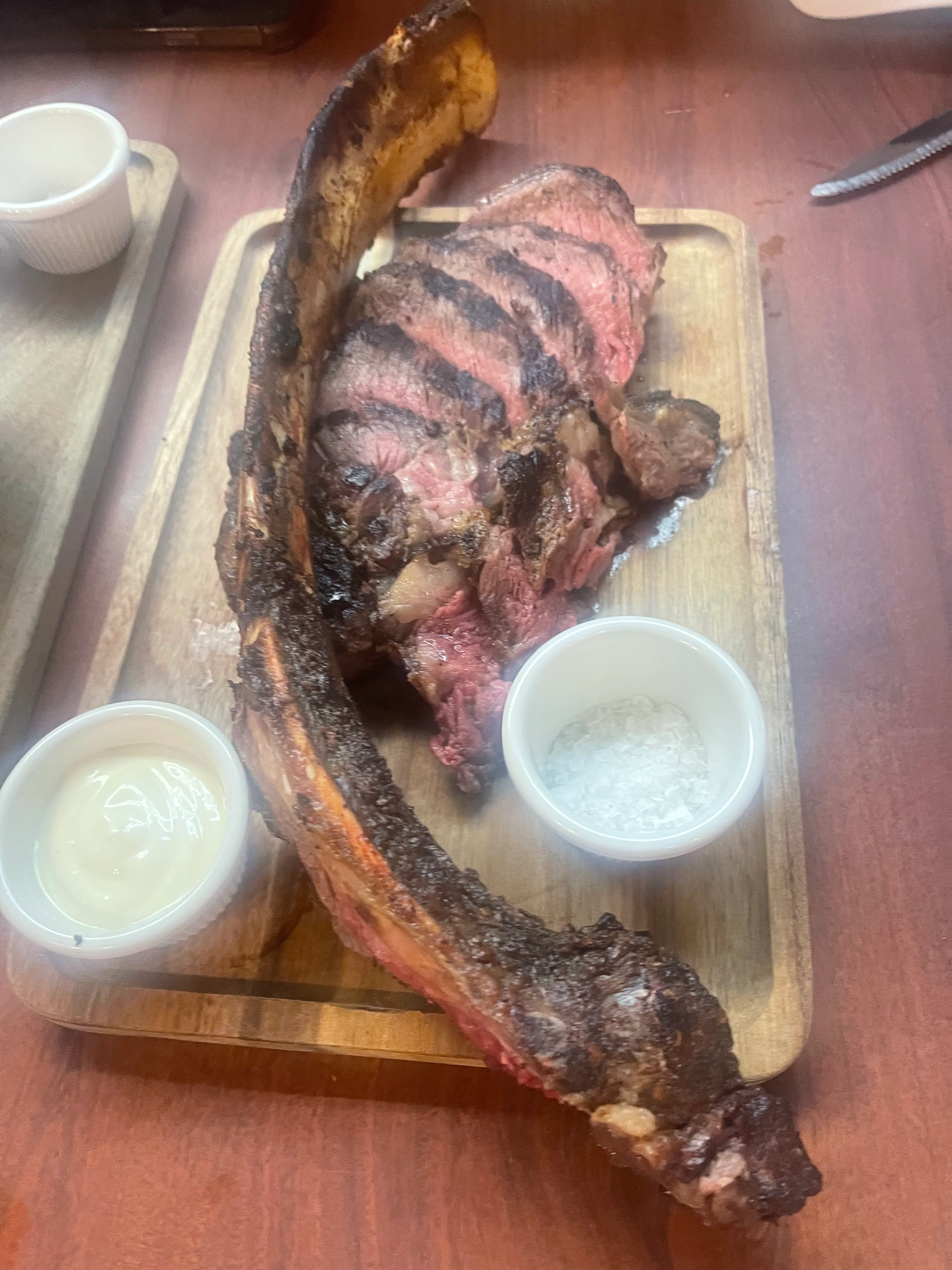 Juicy tomahawk steak served with dipping sauces