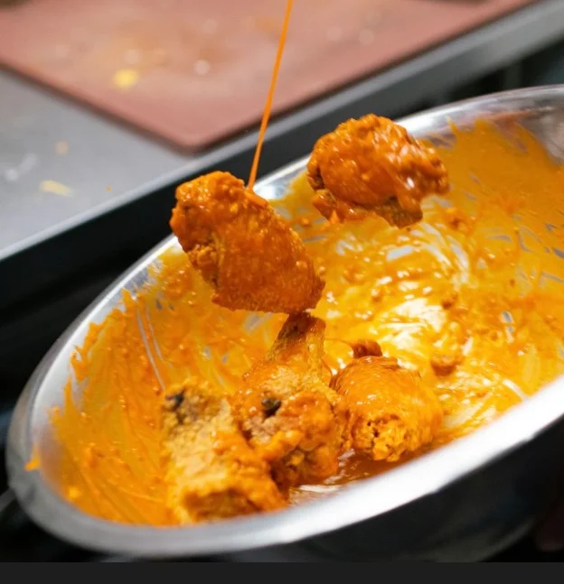 Wings being tossed in a bowl