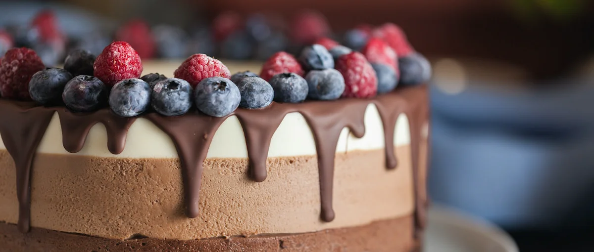 Delicious layered chocolate cake topped with berries and chocolate drizzle.