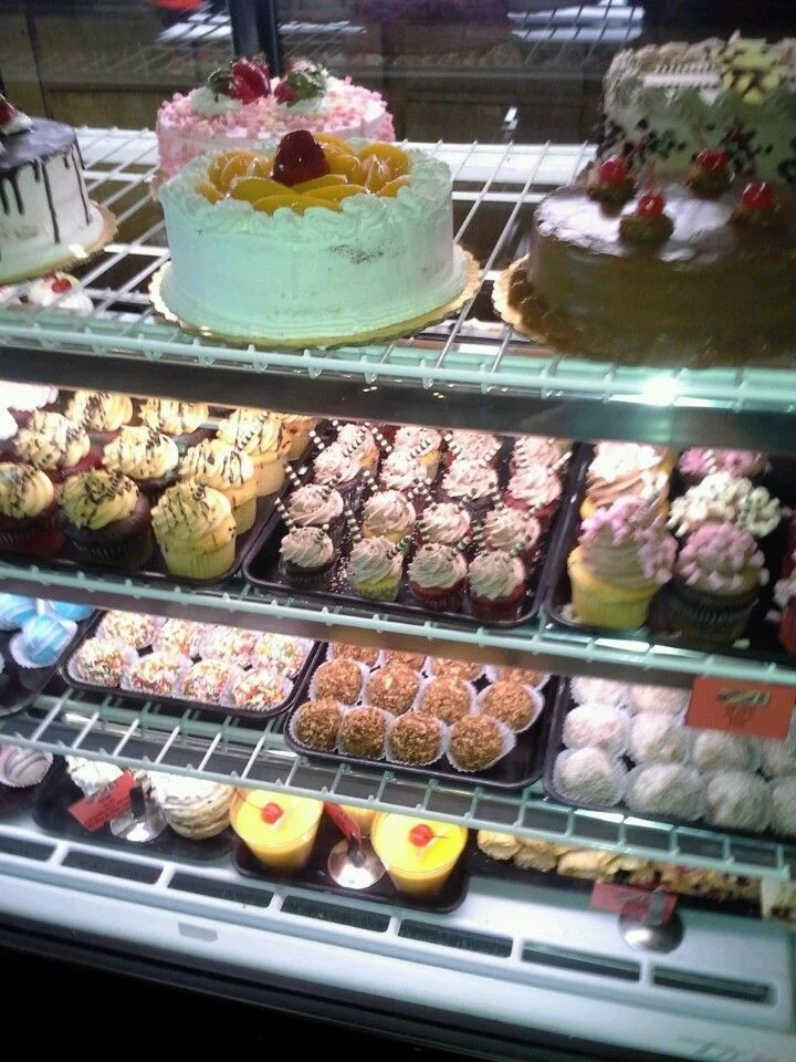 Assorted cakes and cupcakes in a bakery display case