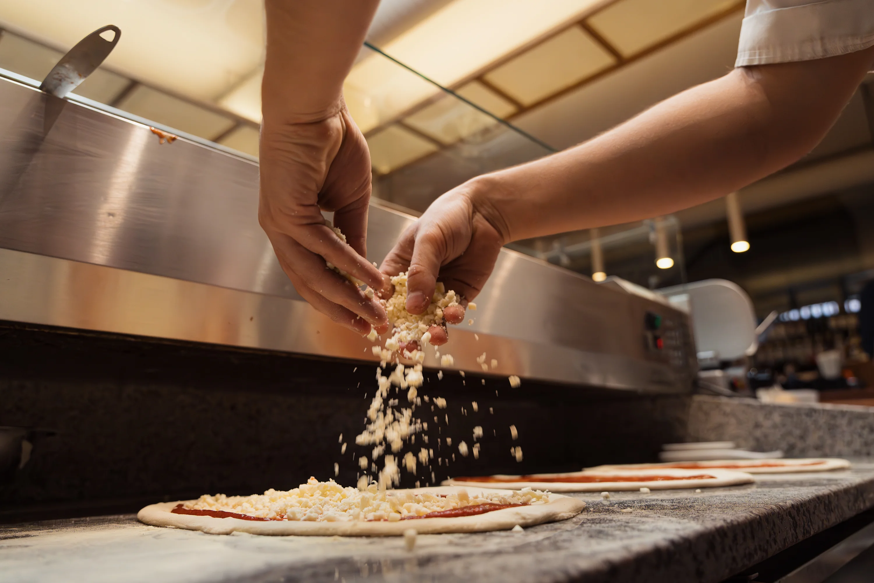 Chef preparing Margherita pizza with cheese and tomato sauce