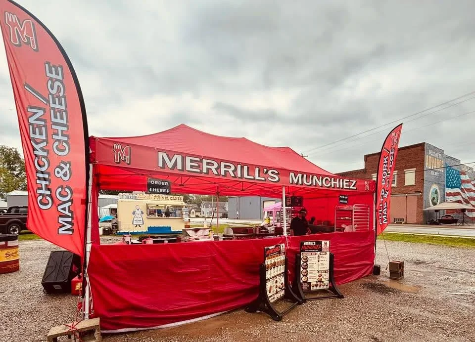 Family-run food stand with red canopy at outdoor event