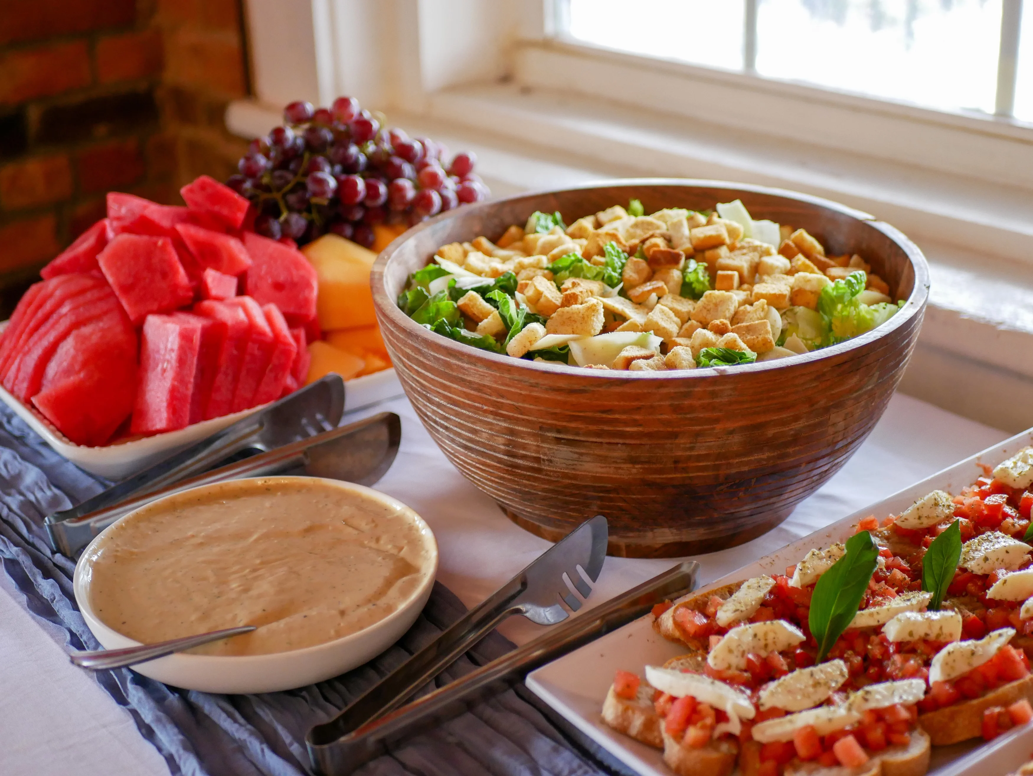 A colorful spread of food including a salad, fruit, and an appetizer, arranged on a table.
