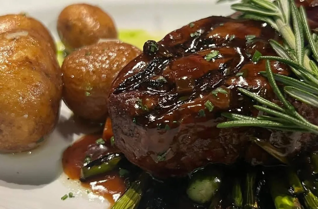 A beautifully plated filet mignon steak with garnishes.