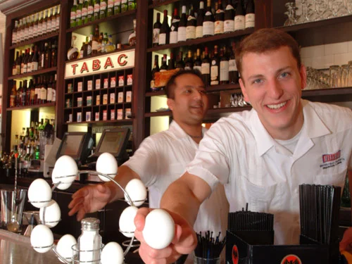 Bartenders preparing drinks at a lively bar with a variety of wines