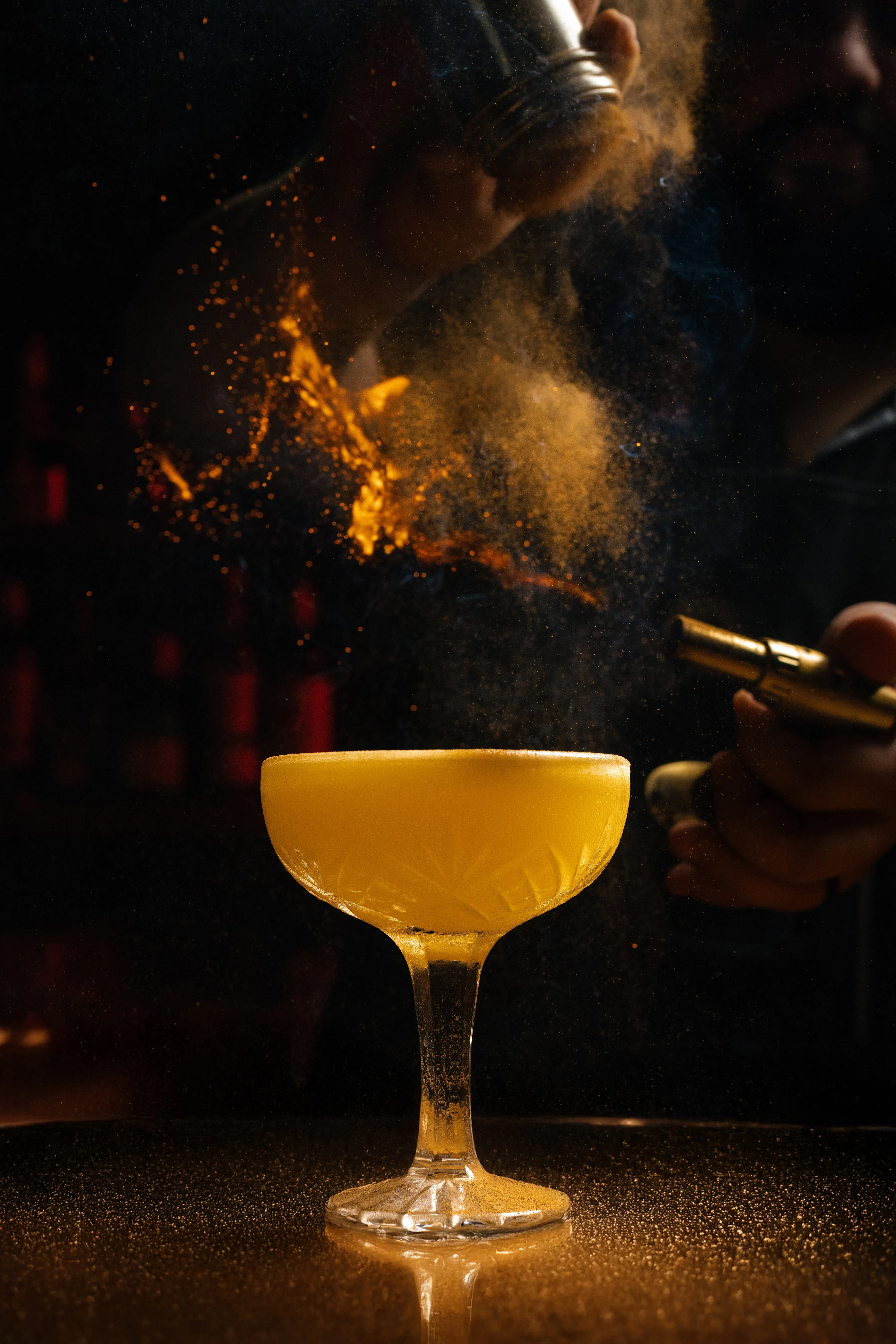 Bartender preparing a vibrant cocktail with a golden hue
