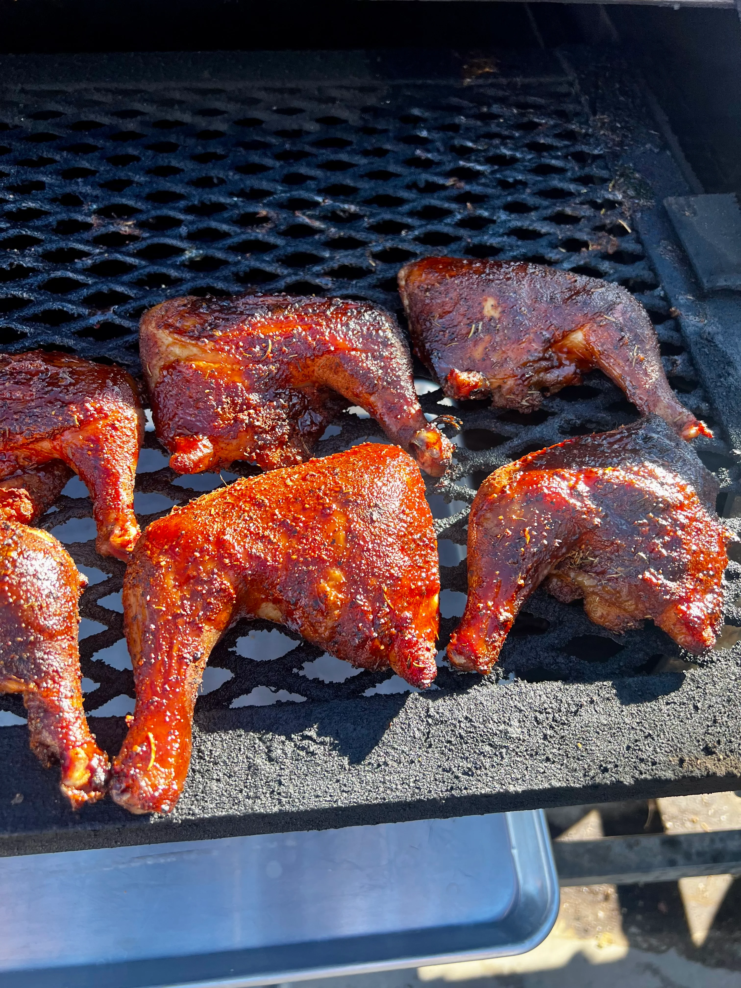 Grilled chicken pieces with a caramelized exterior on a smoker grate.