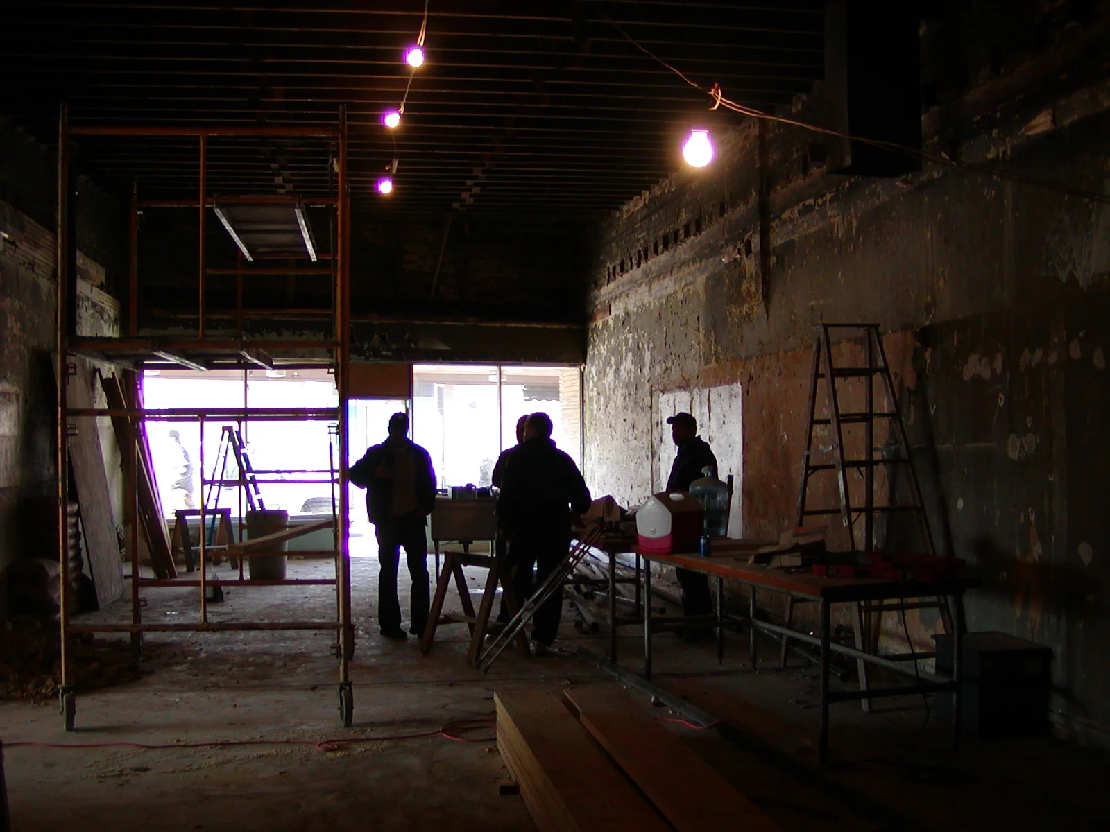 Construction site interior with scaffolding and workers discussing plans