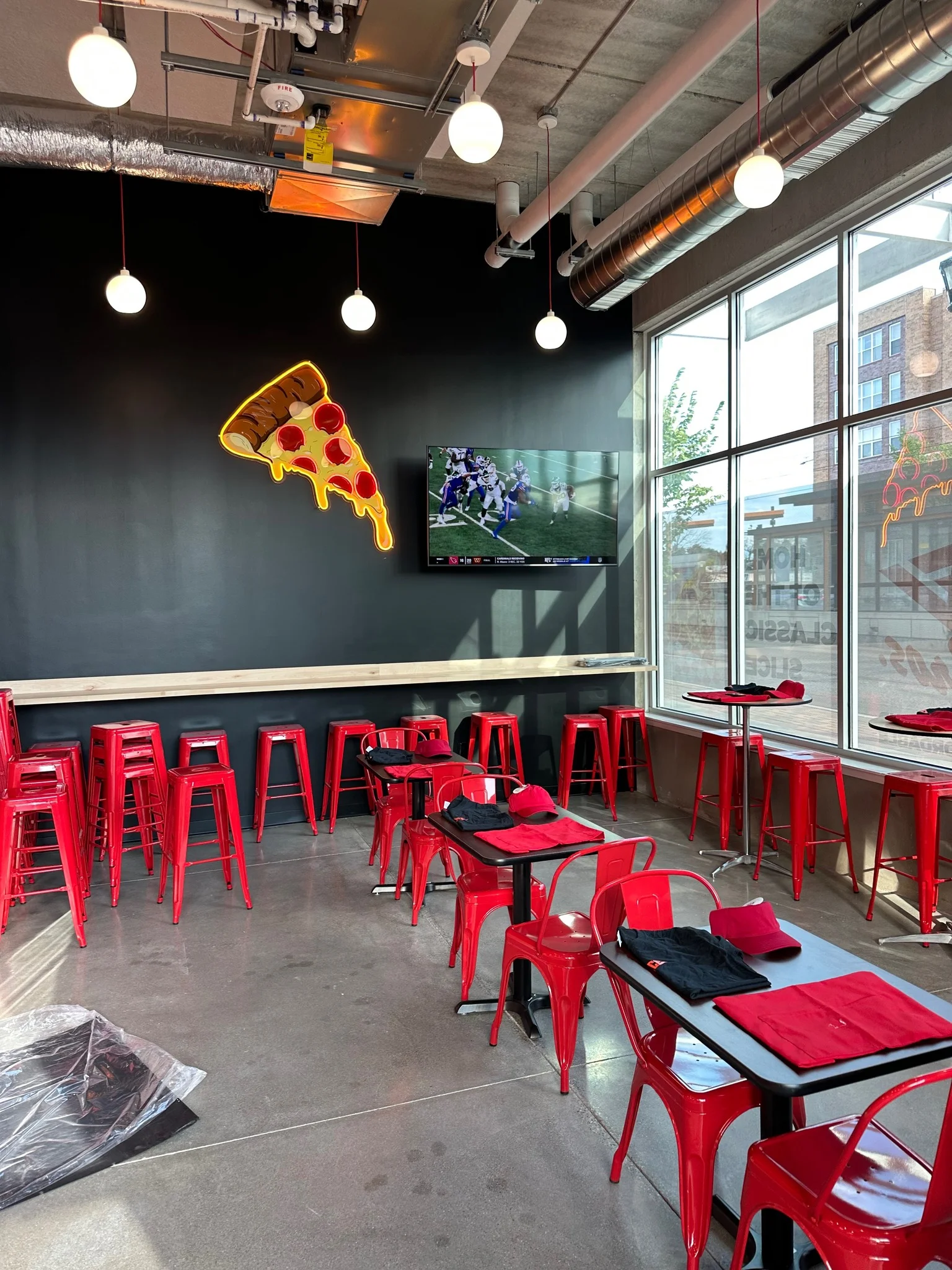 Modern restaurant interior with red stools and pizza decor