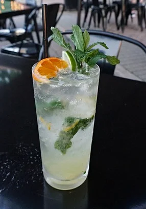 Refreshing mojito cocktail garnished with mint and citrus in a vibrant outdoor setting