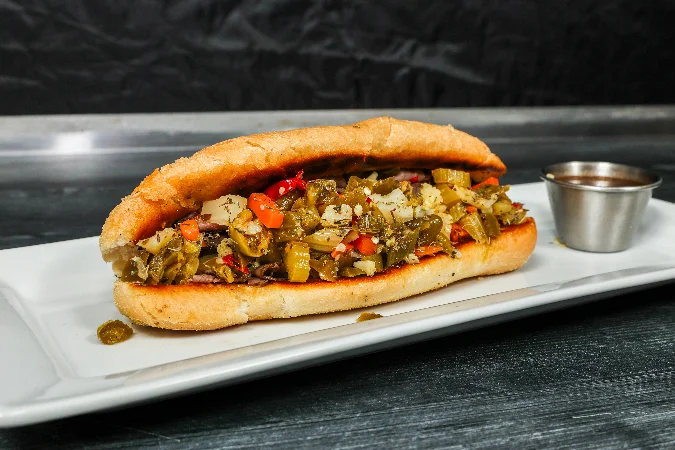 Delicious Italian beef sandwich with toppings on a wooden board.