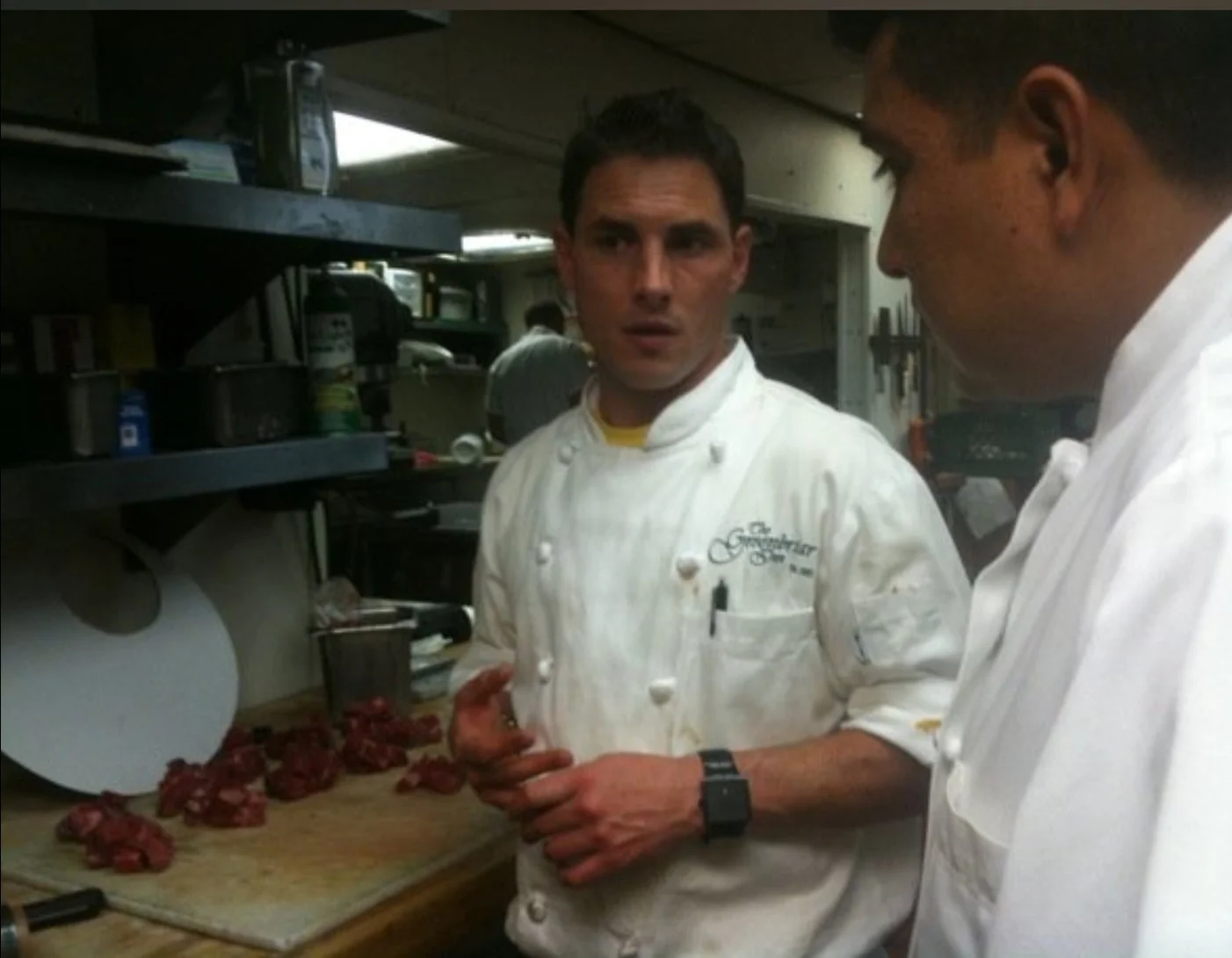 Chefs discussing meat preparation in a restaurant kitchen