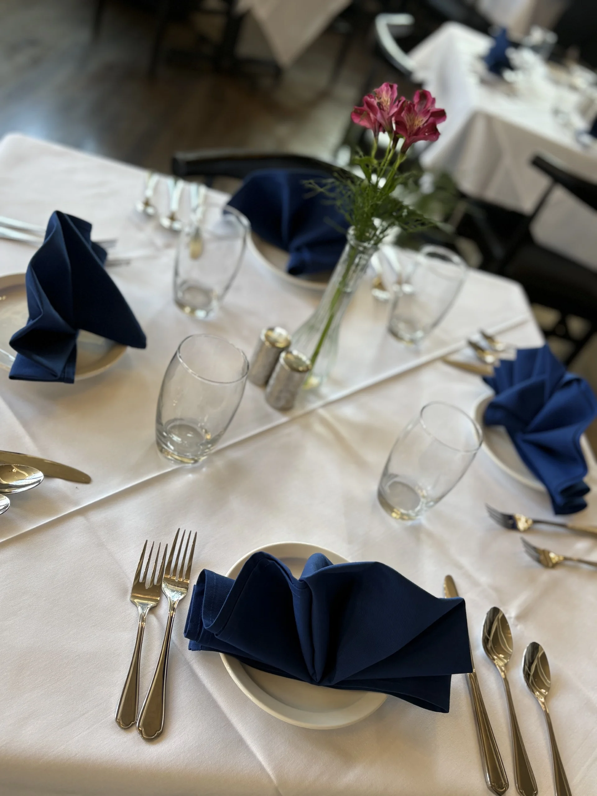 Elegant restaurant table setting with navy napkins and fresh flowers