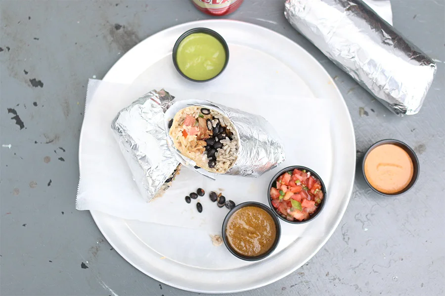Delicious burritos served with fresh salsa and sauces on a metal tray