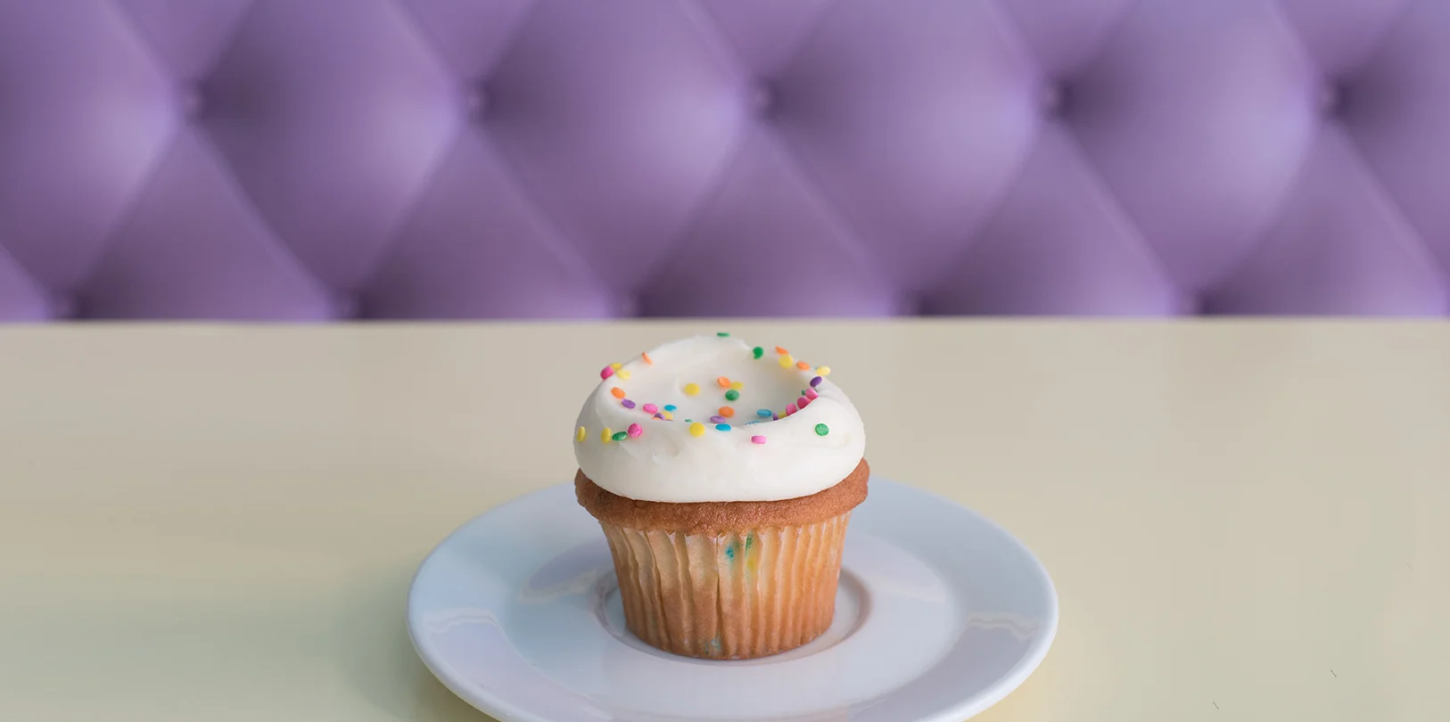 Colorful cupcake with sprinkles on a white plate