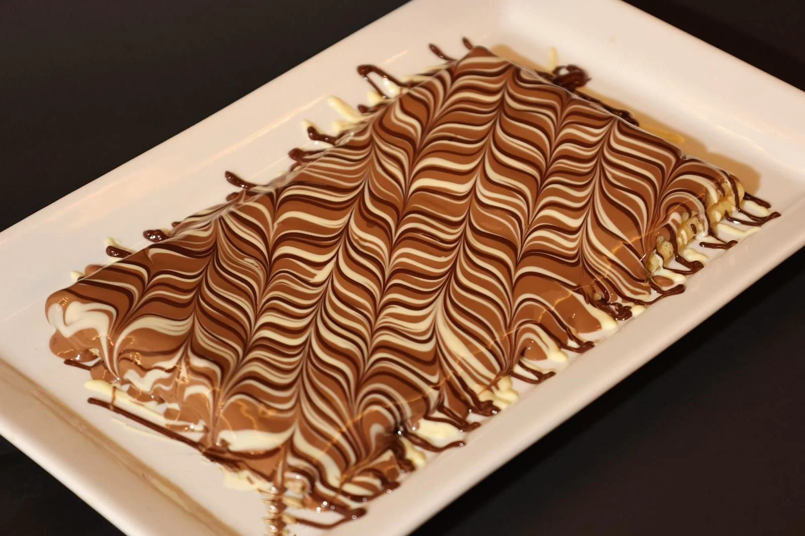 An elegant dessert composed of a chocolate and white striped surface, beautifully designed on a white plate.