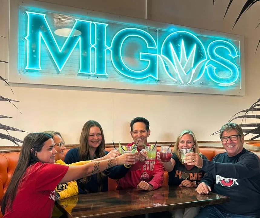 Group of friends toasting with cocktails at Migos restaurant