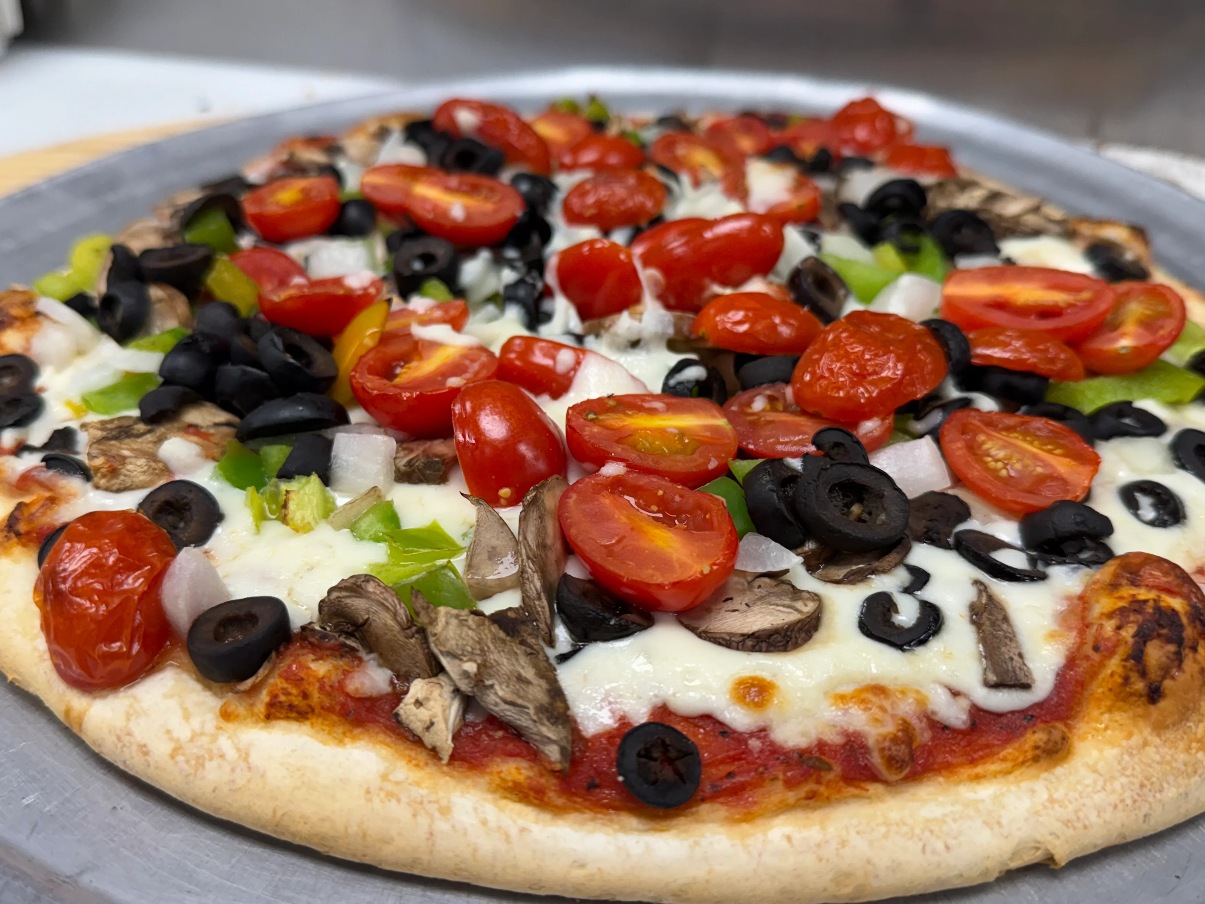 A DiCicco’s pizza topped with tomatoes and black olives