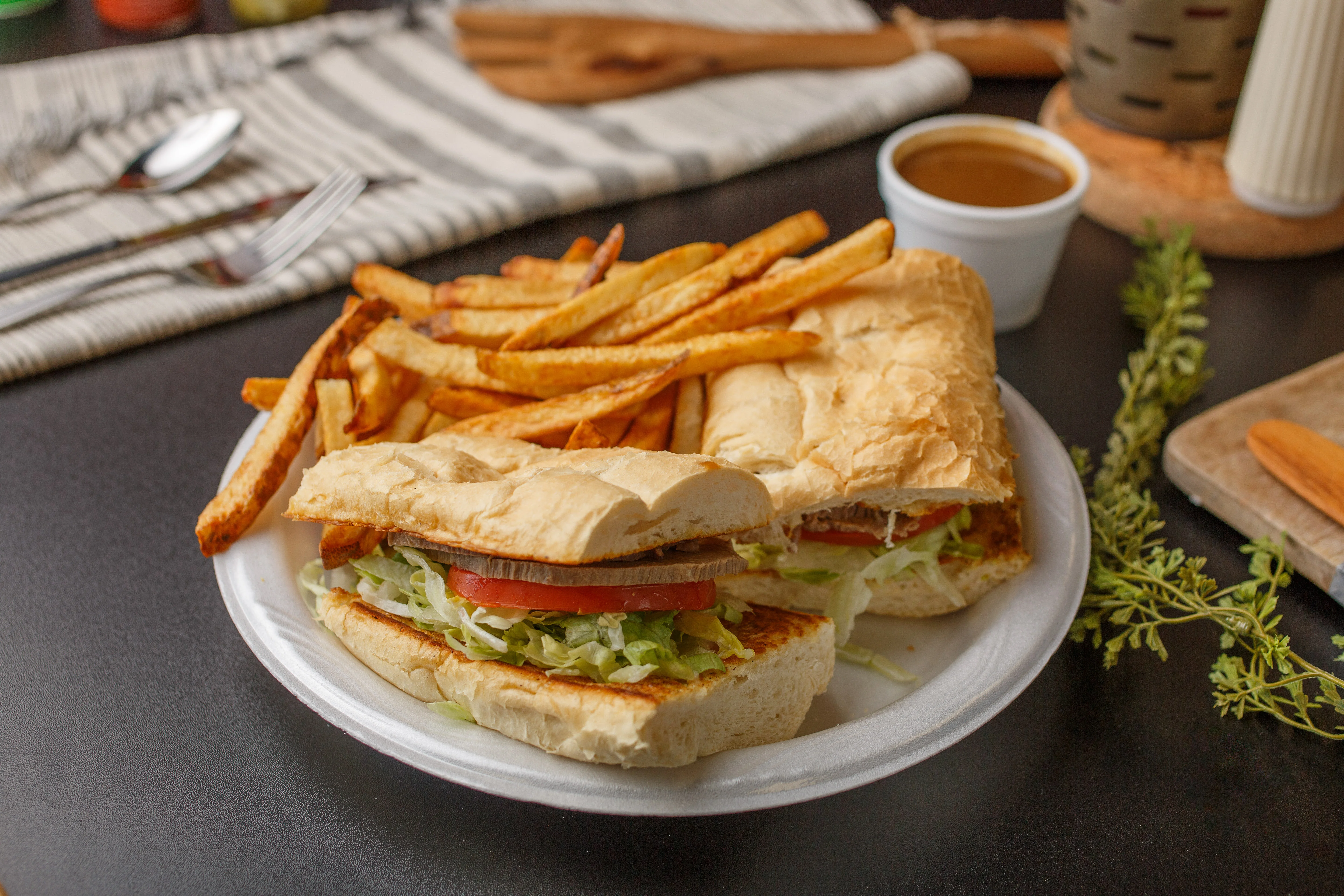 Two sandwiches with lettuce and tomato, served with fries and dipping sauce.