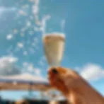 Cheers with a sparkling cocktail against a bright blue sky