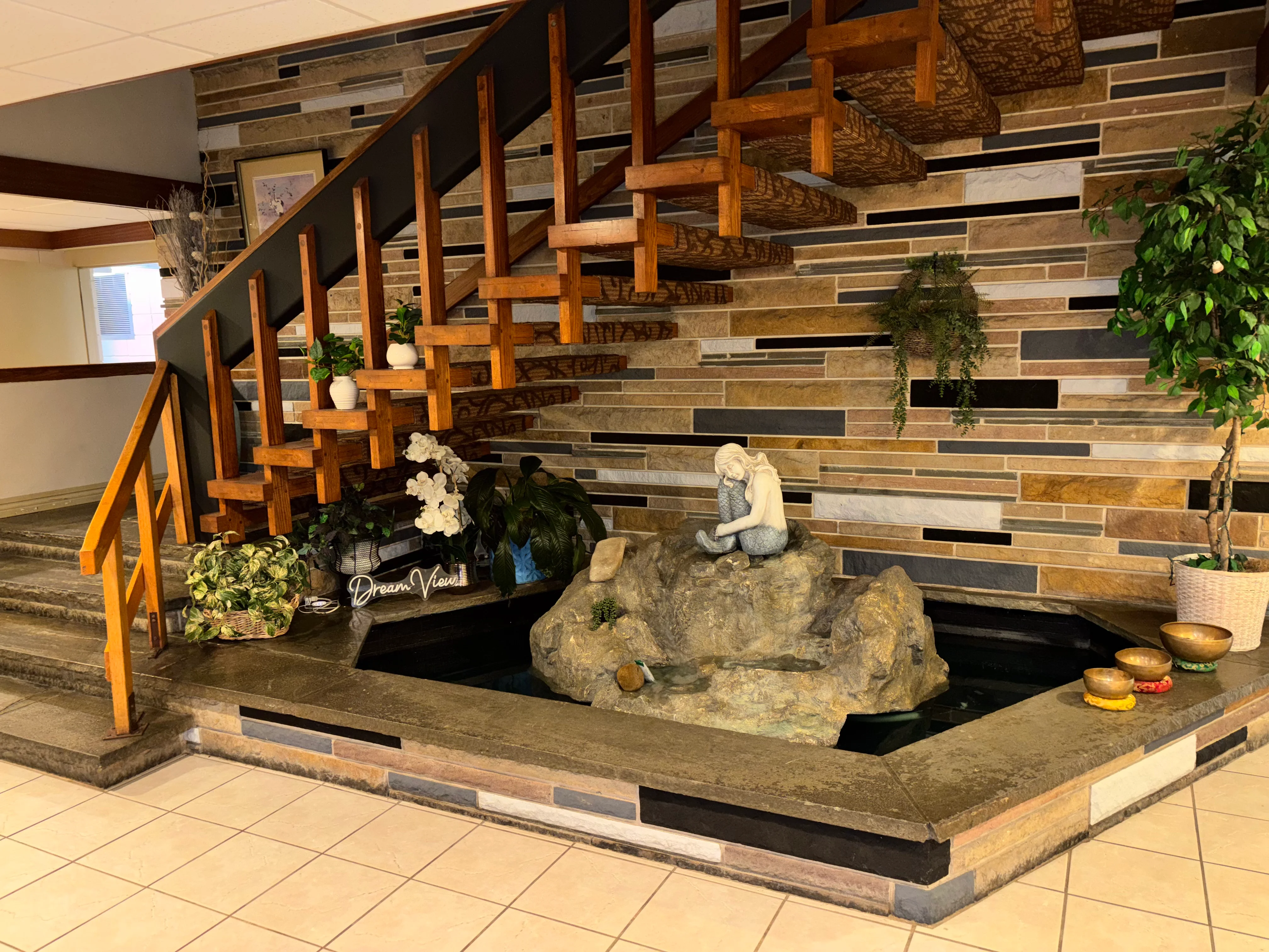 Elegant restaurant interior with wooden staircase and decorative water feature