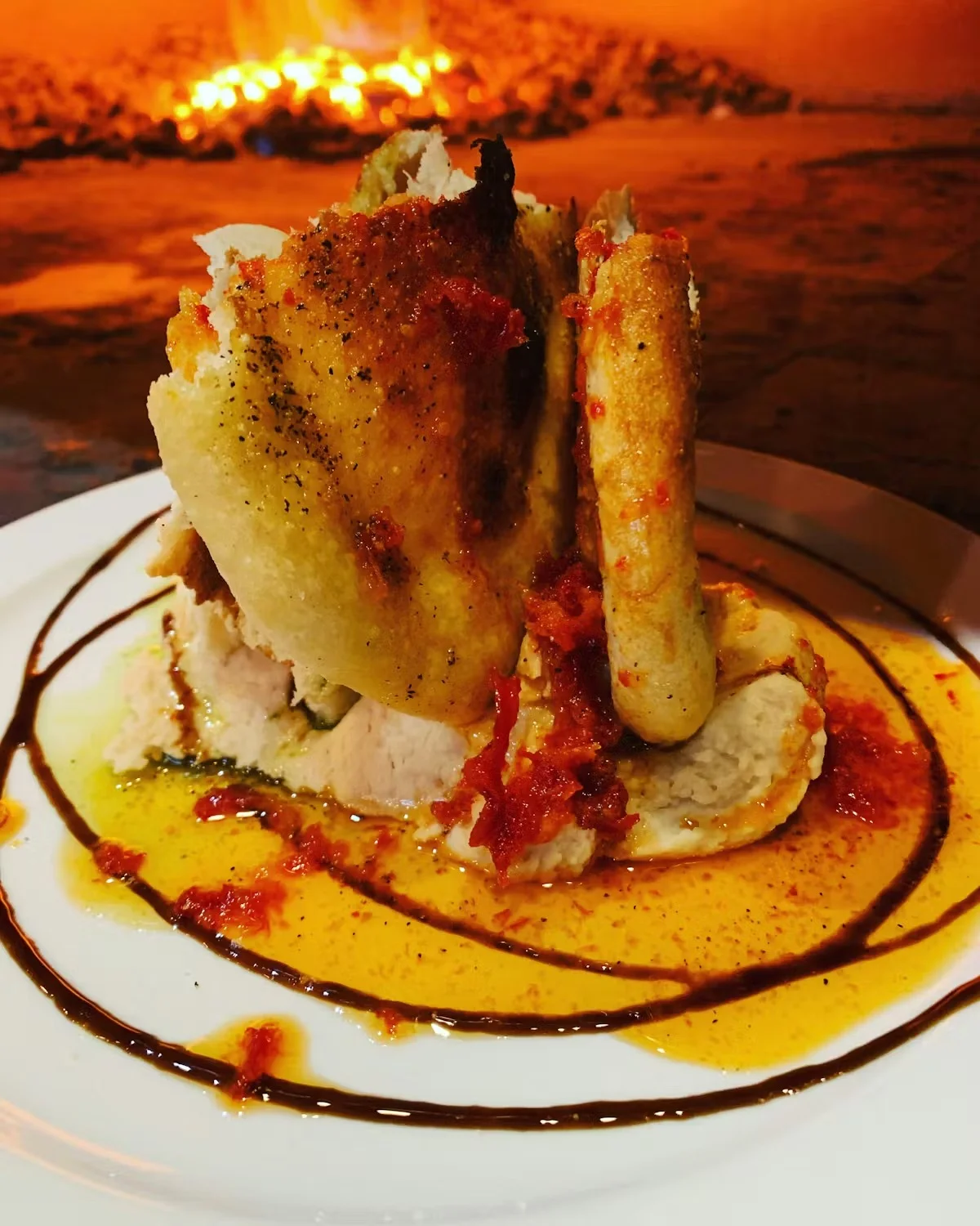 Artfully plated dish with chicken, sauce, and garnishes on a white plate.
