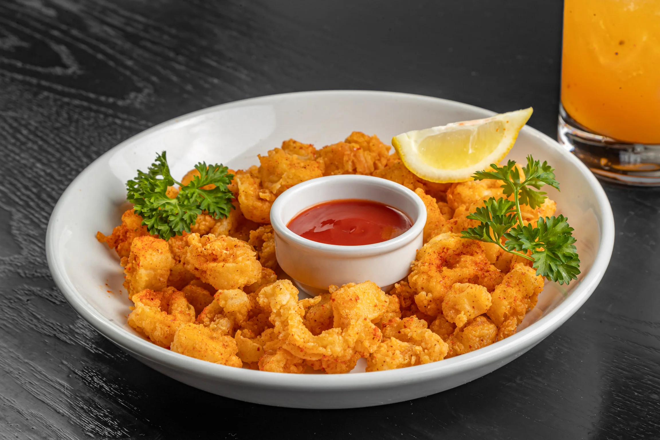 Crispy fried calamari with dipping sauce and lemon wedge