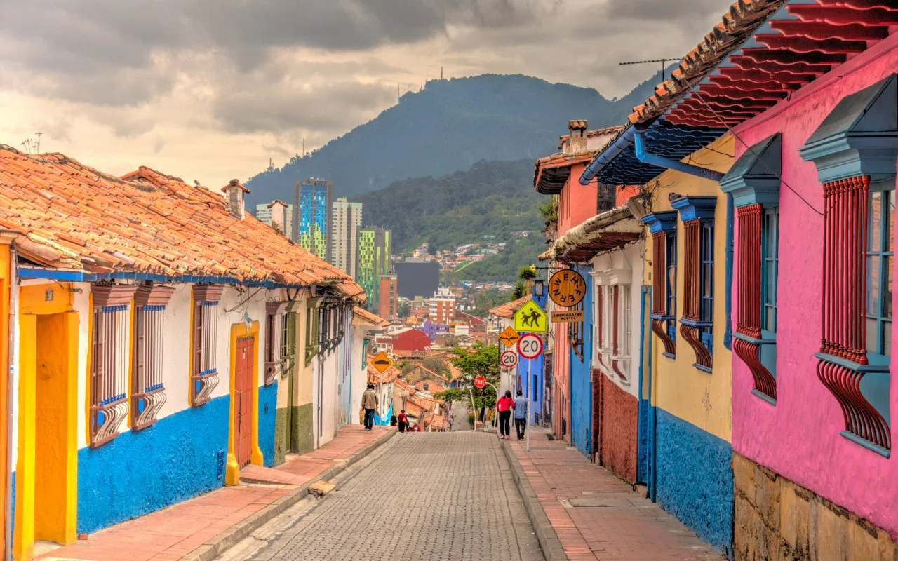 Colorful street view in Bogotá with vibrant houses and mountains in the background