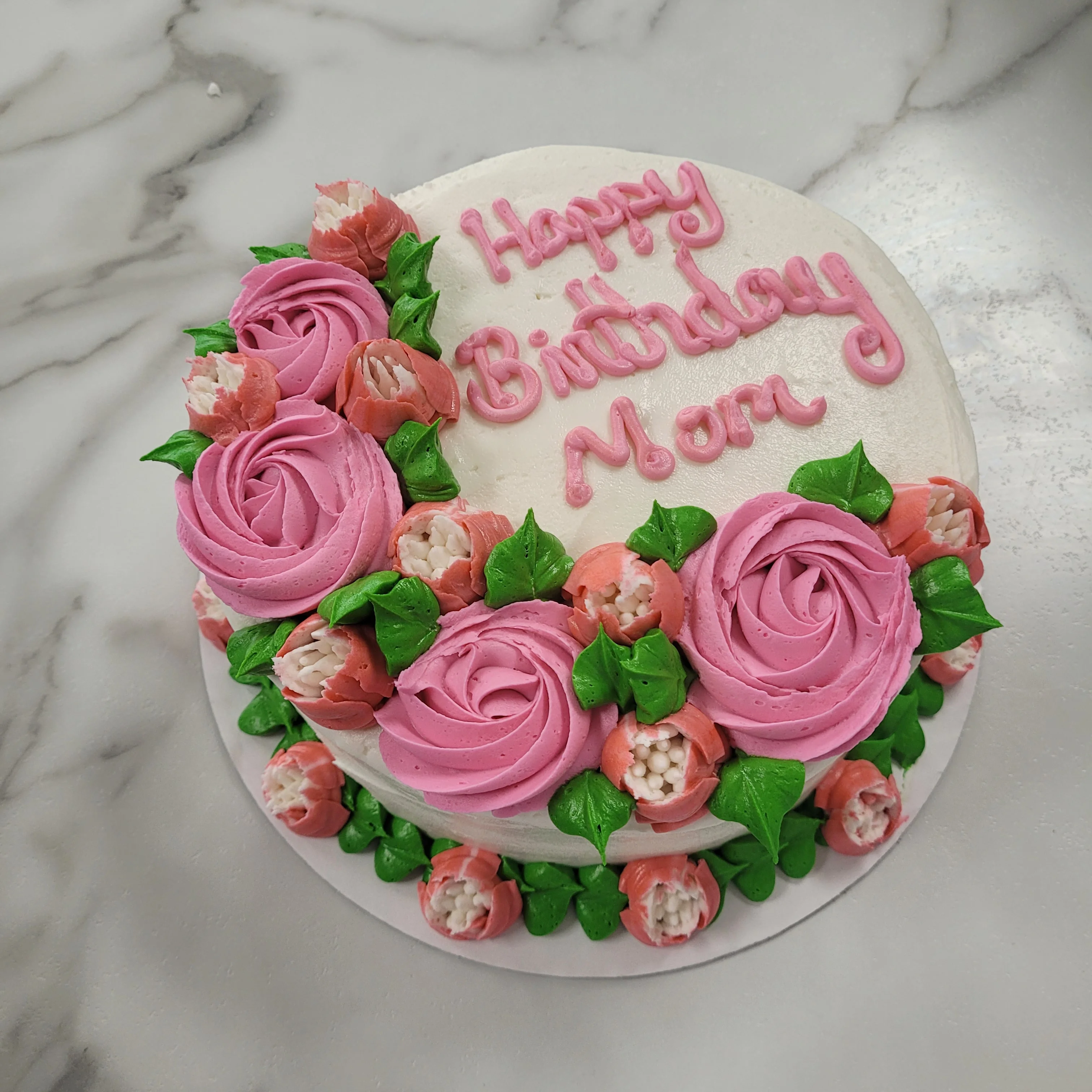 Beautiful birthday cake decorated with pink roses and green leaves