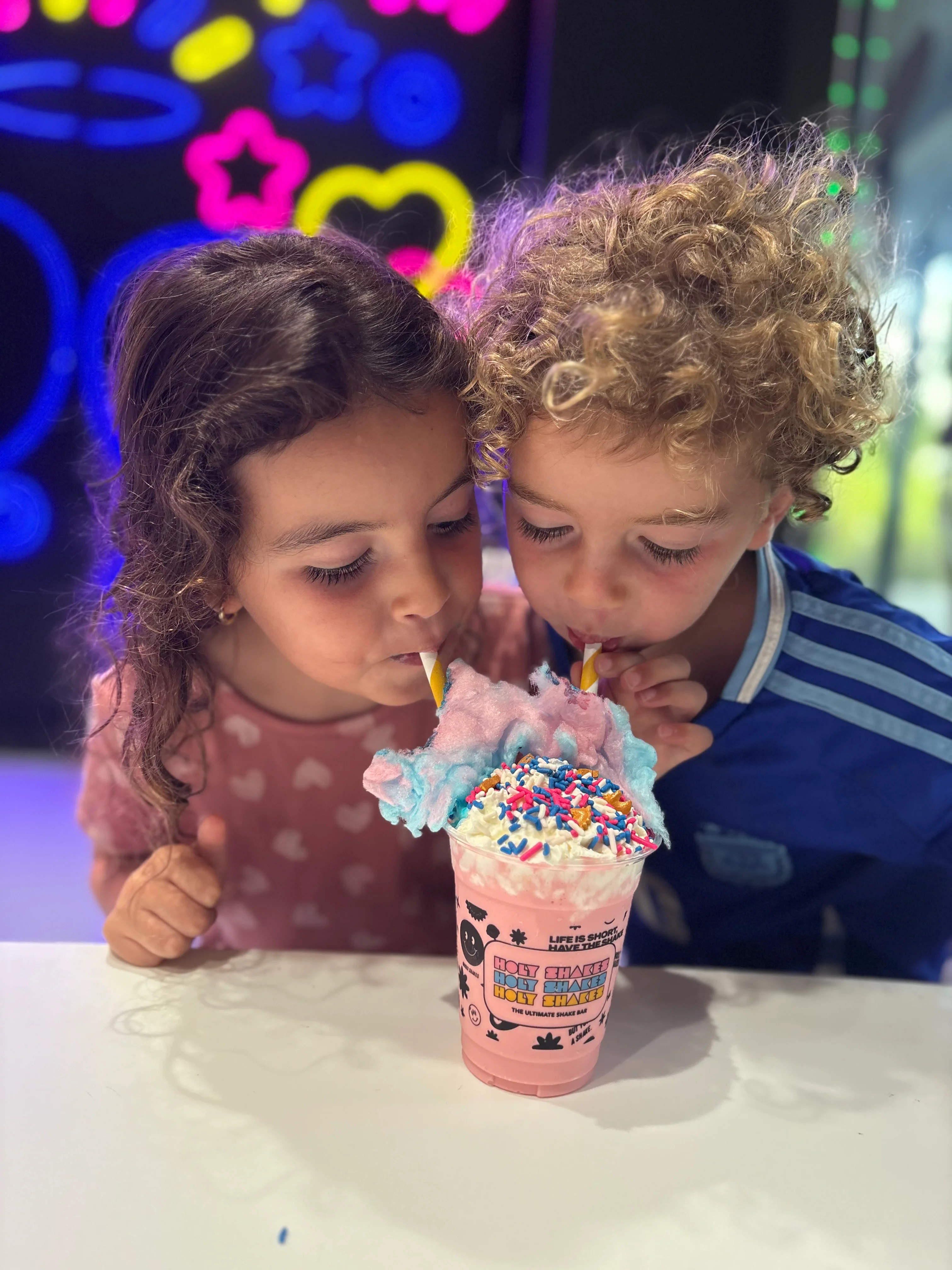 Colorful milkshake topped with cotton candy and sprinkles