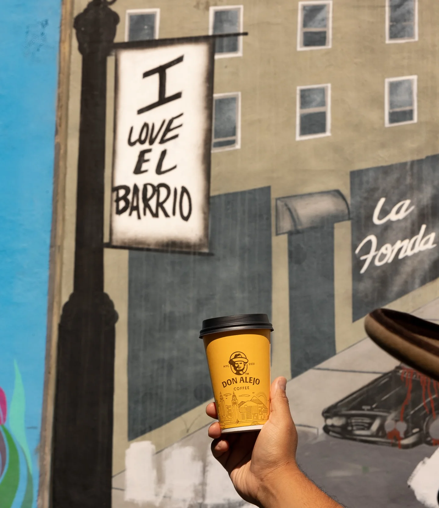 Coffee cup in front of vibrant mural in El Barrio, NYC